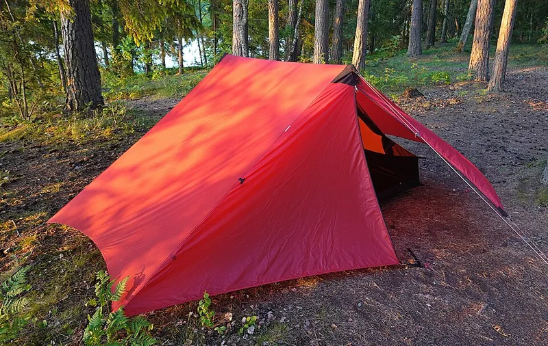 Red tent at a woodland campsite, illustrating the Solo Camping Starter bundle in El Chaltén