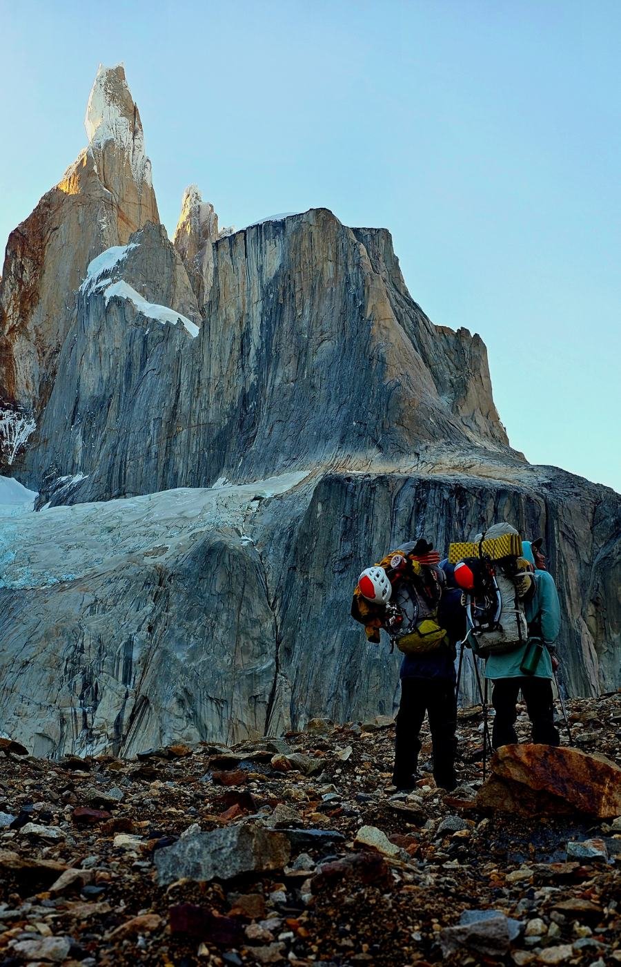 Climbers carrying equipment below granite peaks near El Chaltén